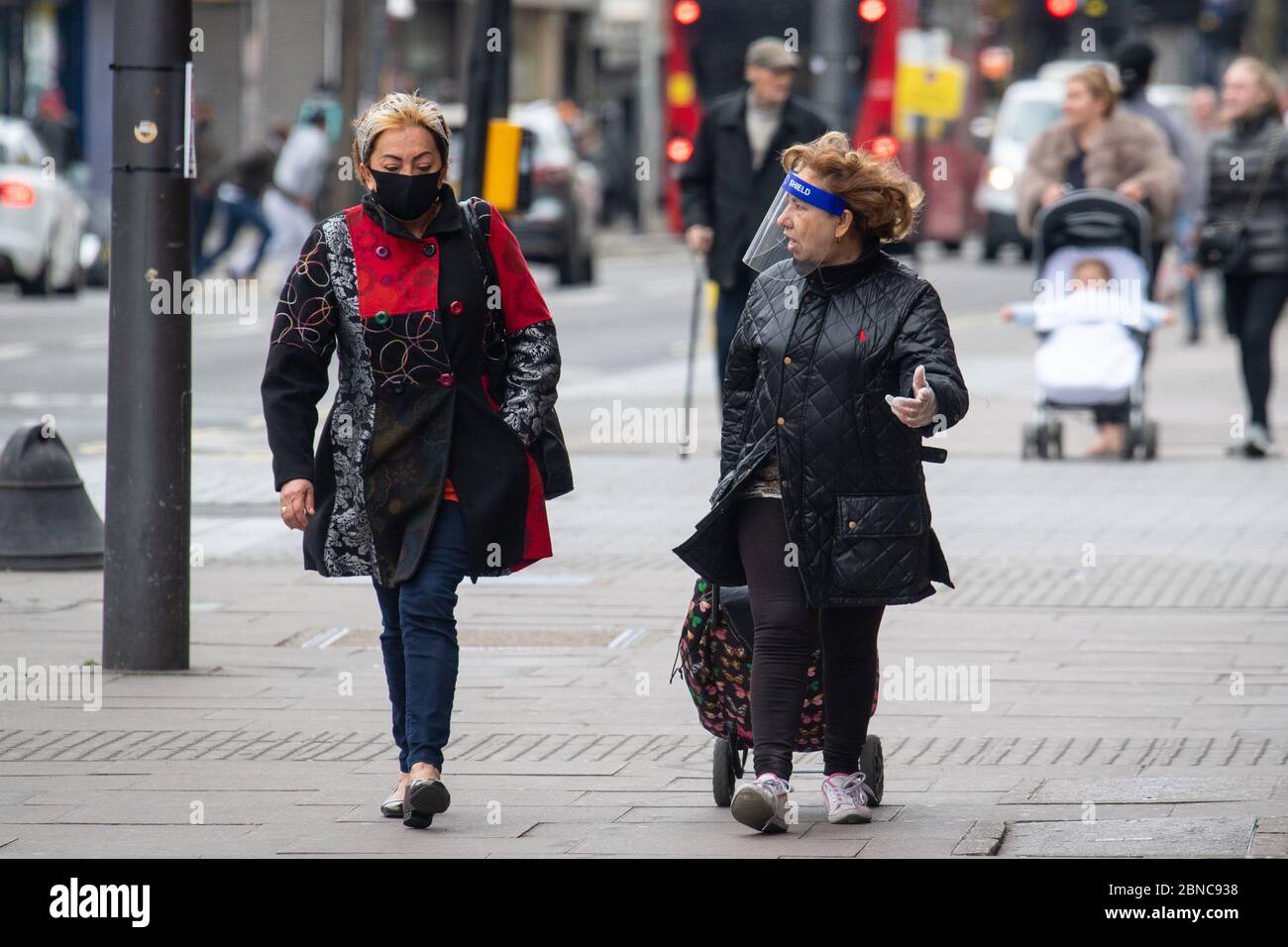 Due donne che indossano una maschera protettiva e uno scudo facciale in plastica su una strada londinese dopo l'annuncio dei piani per portare il paese fuori dalla chiusura. Foto Stock