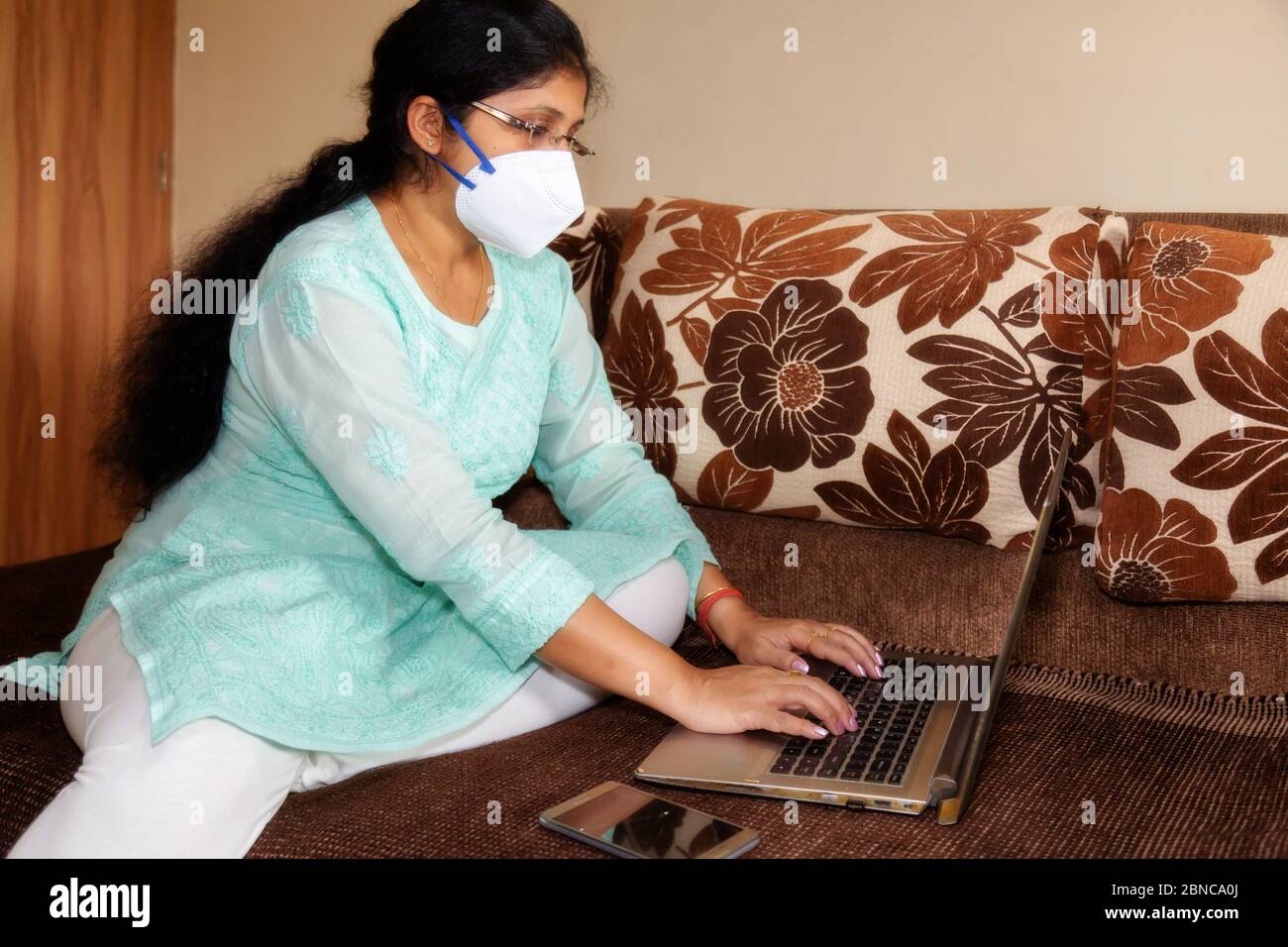 Donna indiana in maschera protettiva lavoro da casa durante il coronavirus blocco Foto Stock