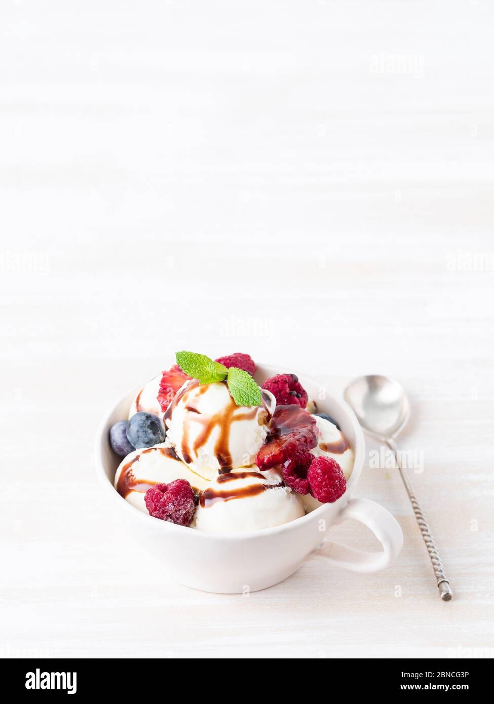 Palle di gelato alla vaniglia in tazza con lampone e mirtilli Foto Stock