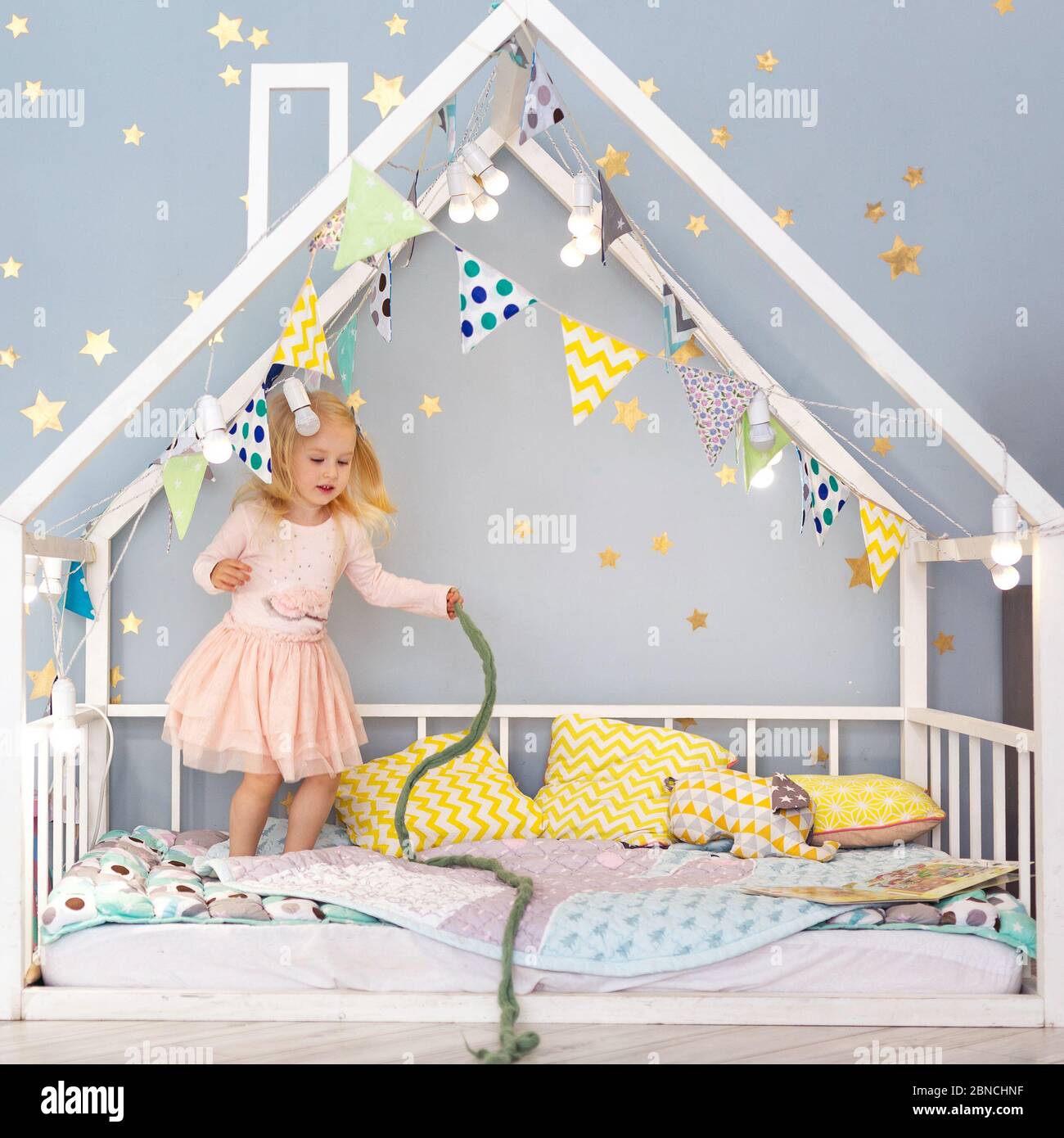 Felice 3 anni ragazza avendo divertimento in casa letto Foto Stock