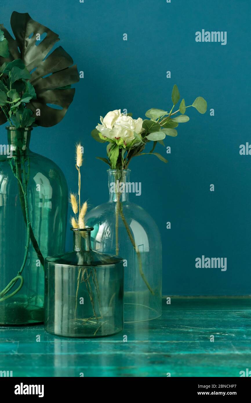 Fiori artificiali e piante secche in vasi trasparenti sul pavimento contro  parete blu Foto stock - Alamy