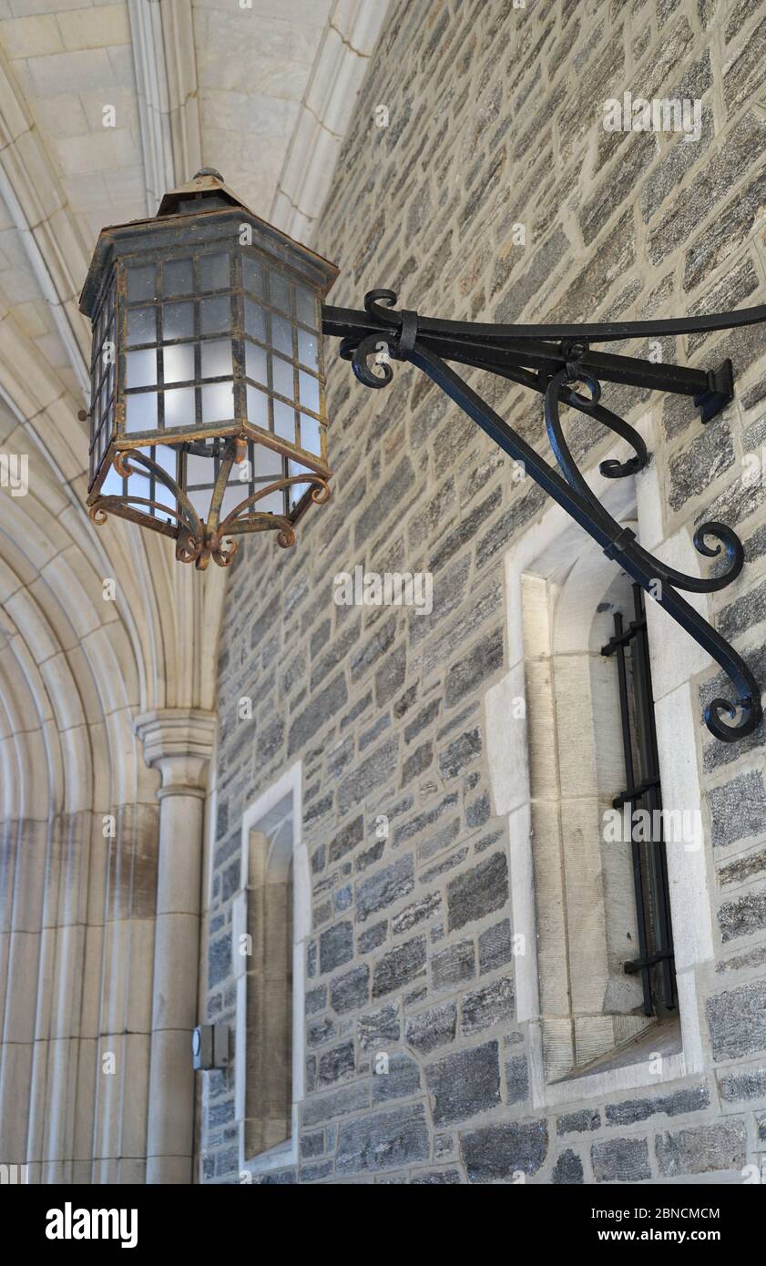 Una applique ornata attaccata ad un vecchio muro di pietra con ferro battuto nero. Foto Stock