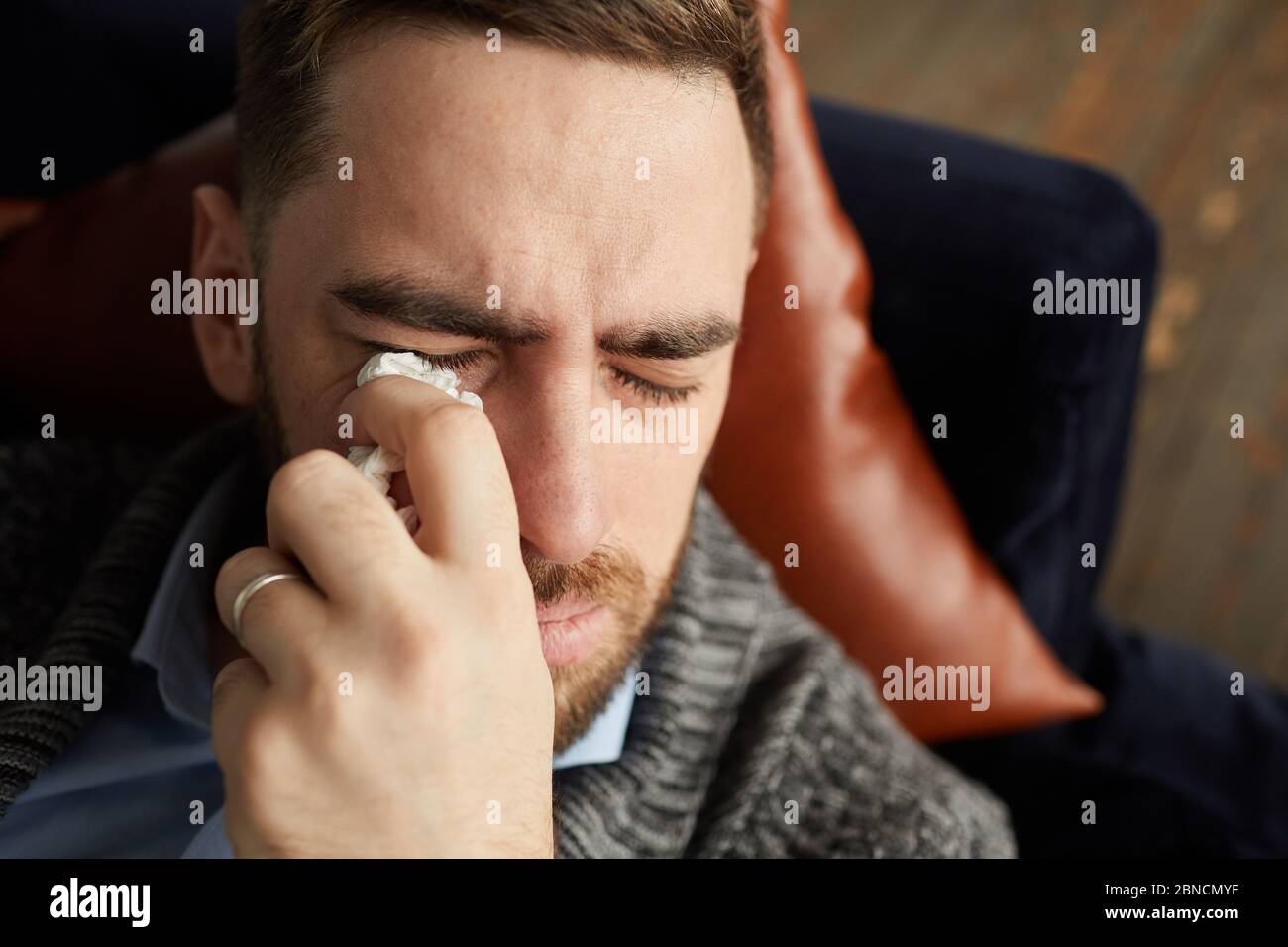 Primo piano di uomo triste che giace su divano e gridando che gli strofina  le lacrime con fazzoletto Foto stock - Alamy