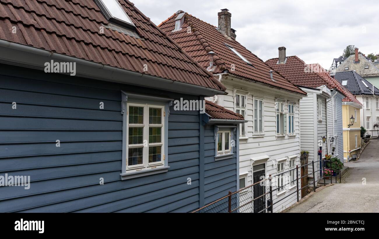 Accoglienti case tradizionali in legno grigio e bianco con tetti rossi. Strade di architettura scandinava a Bergen, Norvegia. Moody città Foto Stock