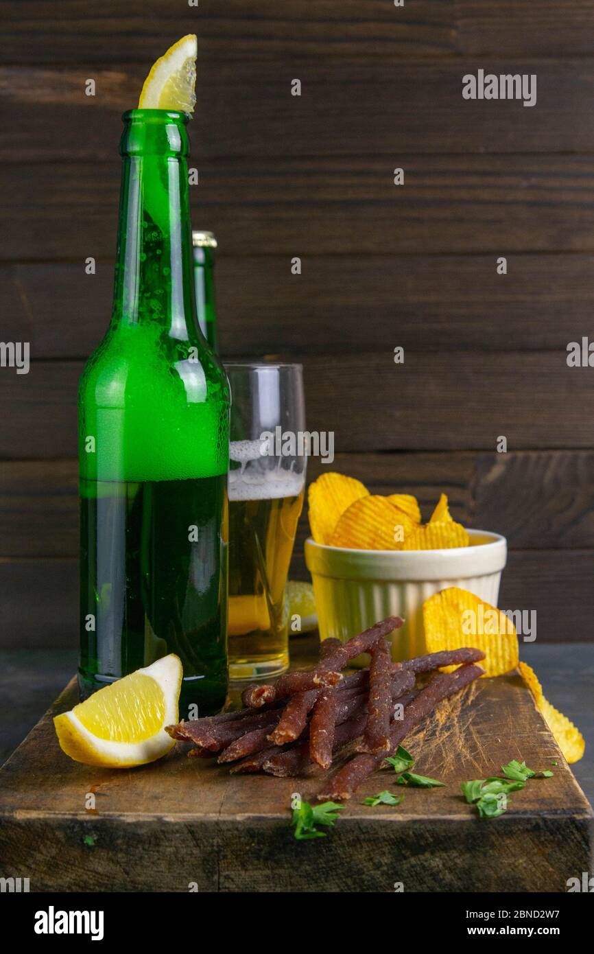 Spuntino al caviale di pesce con birra, patatine di limone e patata su un pannello di legno scuro. Snack a base di pesce con birra. Primo piano Foto Stock