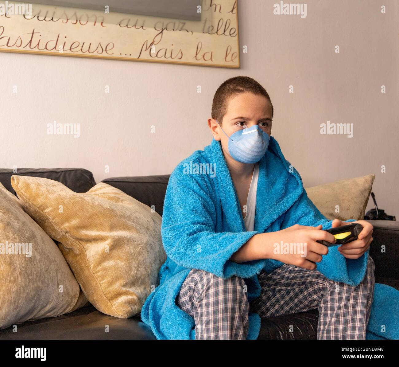 Durante la pandemia del ragazzo COVID-19 che gioca a casa con una console Foto Stock