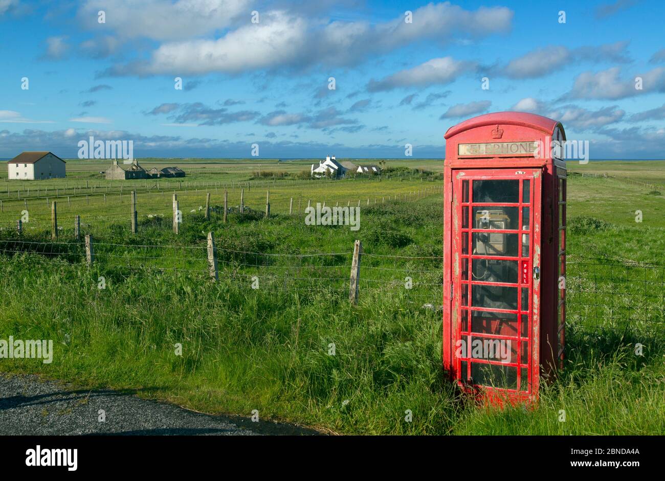 Telefono rosso box e case di crociferi a Baile Mor, Uist del Nord, Ebridi esterne, Scozia, Regno Unito, giugno 2015. Foto Stock