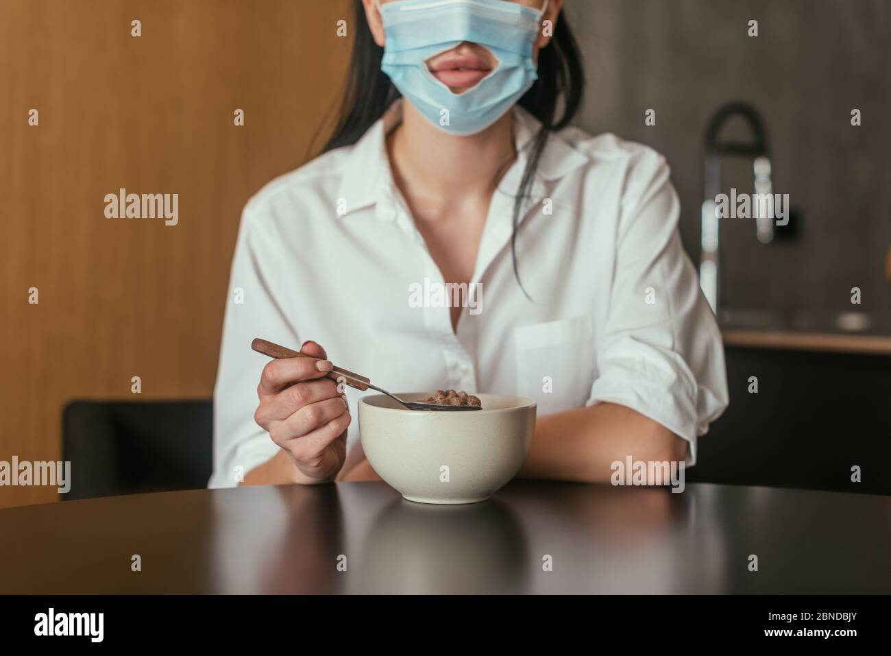 vista-tagliata-della-donna-in-maschera-medica-con-foro-per-bocca-che-tiene-il-cucchiaio-vicino-ciotola-con-la-colazione-2bndbjy.jpg