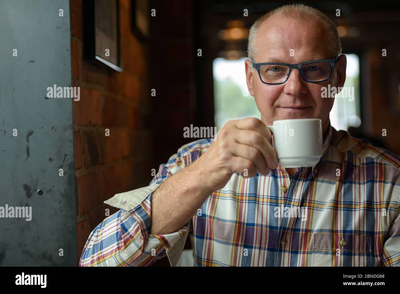 Ritratto di un uomo d'affari anziano che beve caffè presso la caffetteria Foto Stock