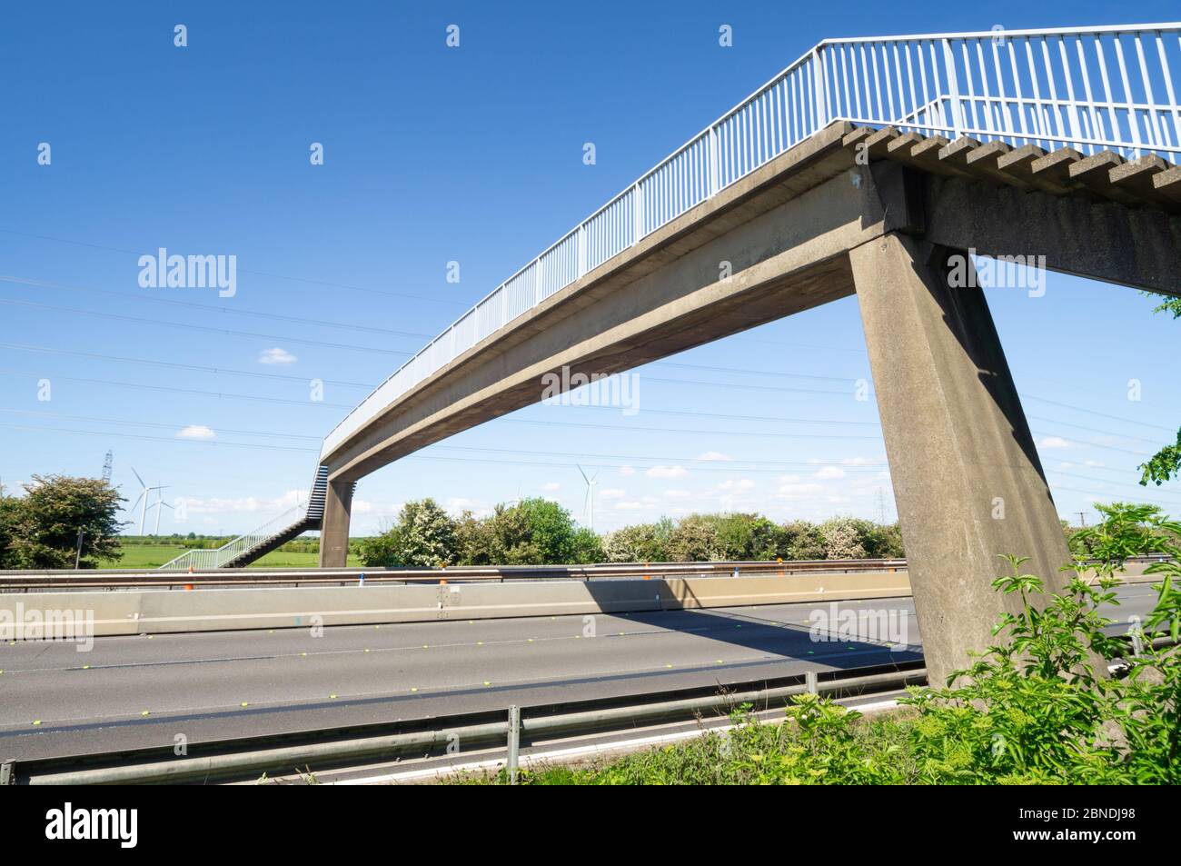 Ponte autostradale sulla M56 vicino a Frodsham, vuoto senza traffico e cielo blu con turbine eoliche, Cheshire, Inghilterra, Regno Unito Foto Stock