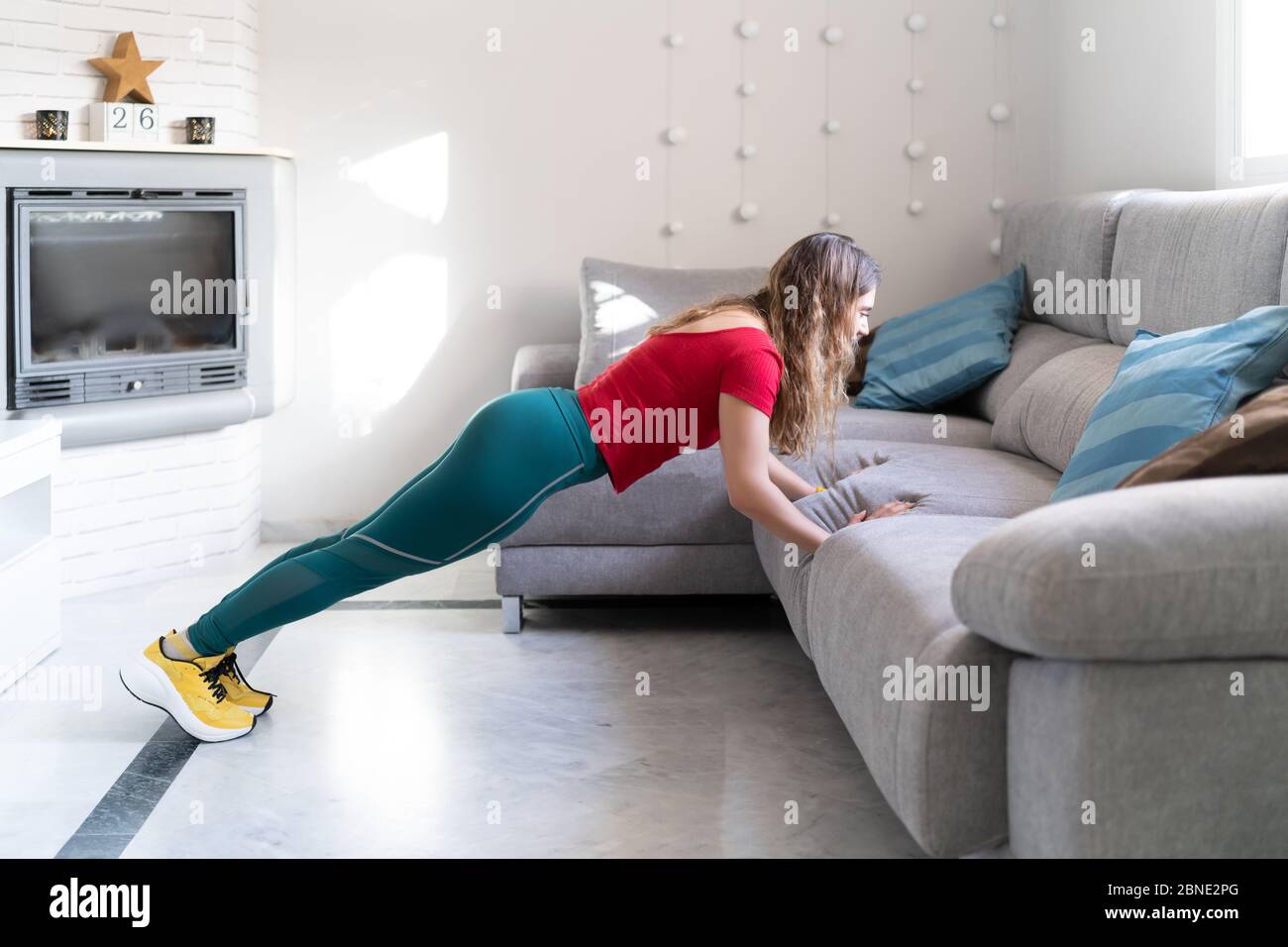 donna che pratica sport facendo push-up sul divano a casa Foto Stock