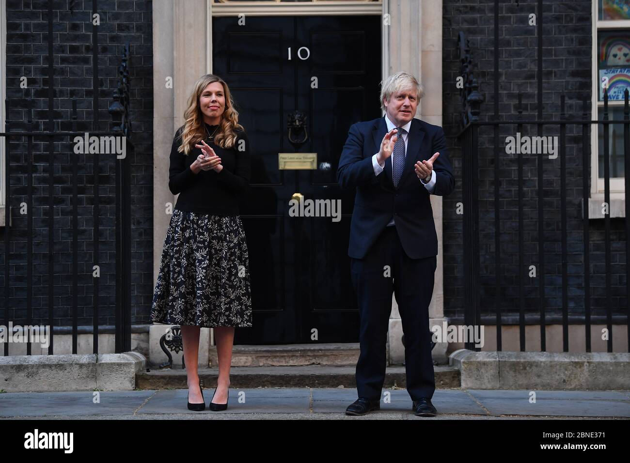 Il primo ministro Boris Johnson e il suo partner Carrie Symonds, si trovano a Downing Street, Londra, per unirsi agli applausi per salutare gli eroi locali durante il Clap for Carers di giovedì per riconoscere e sostenere i lavoratori e gli assistenti di NHS che combattono la pandemia del coronavirus. Foto Stock