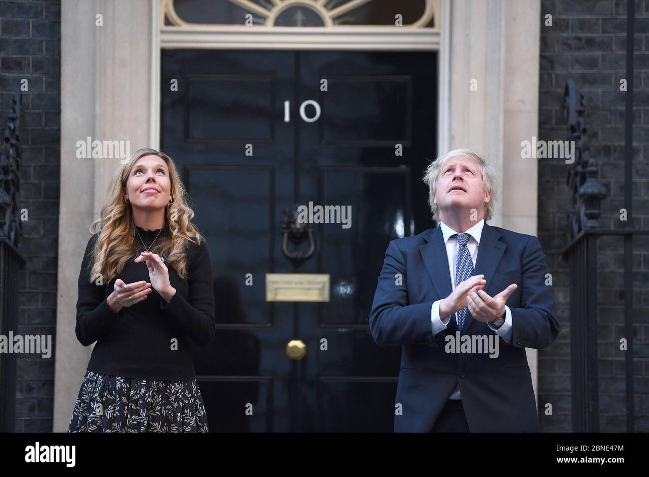 Il primo ministro Boris Johnson e il suo partner Carrie Symonds, si trovano a Downing Street, Londra, per unirsi agli applausi per salutare gli eroi locali durante il Clap for Carers di giovedì per riconoscere e sostenere i lavoratori e gli assistenti di NHS che combattono la pandemia del coronavirus. Foto Stock