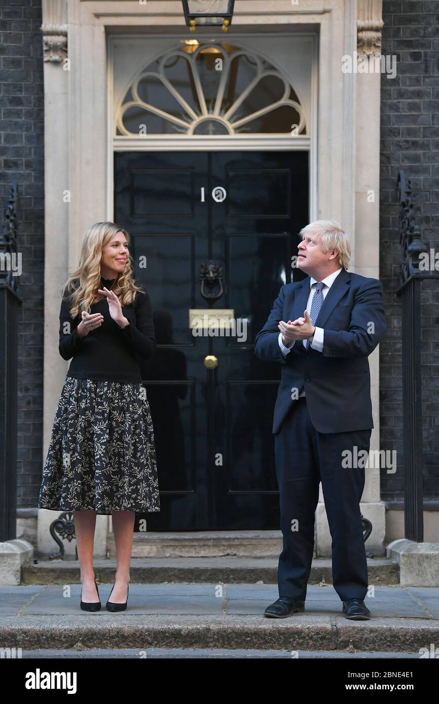 Il primo ministro Boris Johnson e il suo partner Carrie Symonds, si trovano a Downing Street, Londra, per unirsi agli applausi per salutare gli eroi locali durante il Clap for Carers di giovedì per riconoscere e sostenere i lavoratori e gli assistenti di NHS che combattono la pandemia del coronavirus. Foto Stock
