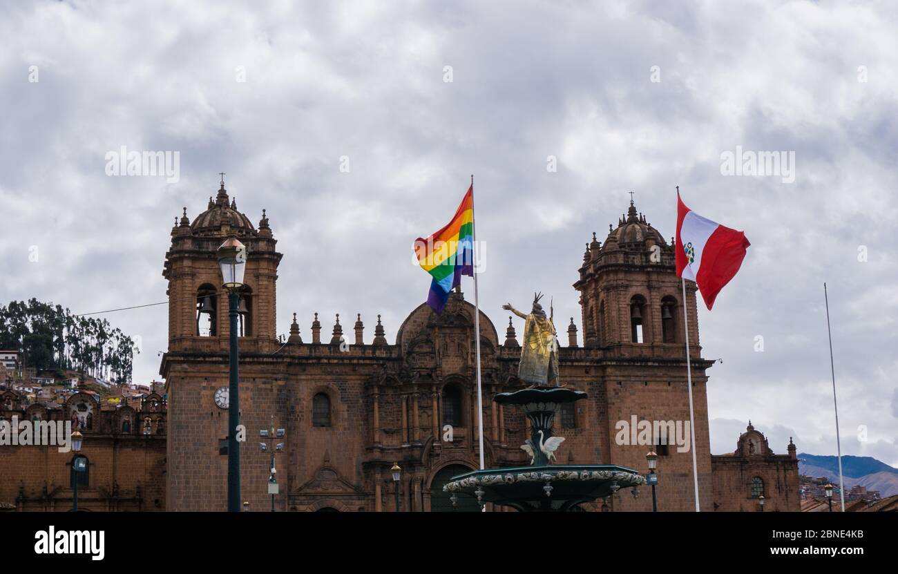Facciata di una cattedrale gotica di mattoni con bandiere del Perù e lgtb di fronte. Cattedrale di Cuzco in Perù Foto Stock