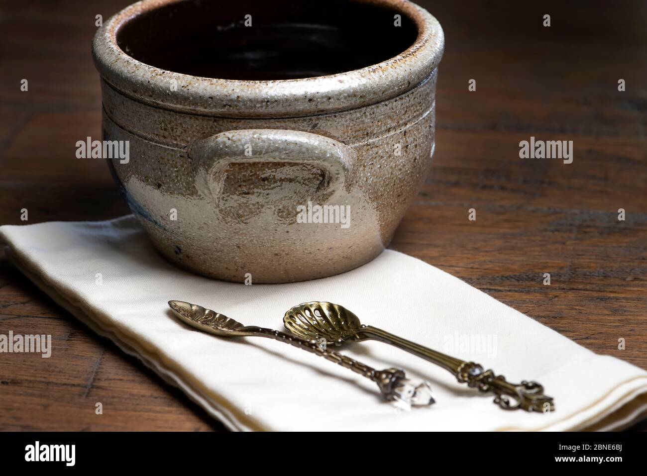 Ciotola in ceramica d'epoca con cucchiai antichi su tovagliolo su un tavolo di legno Foto Stock