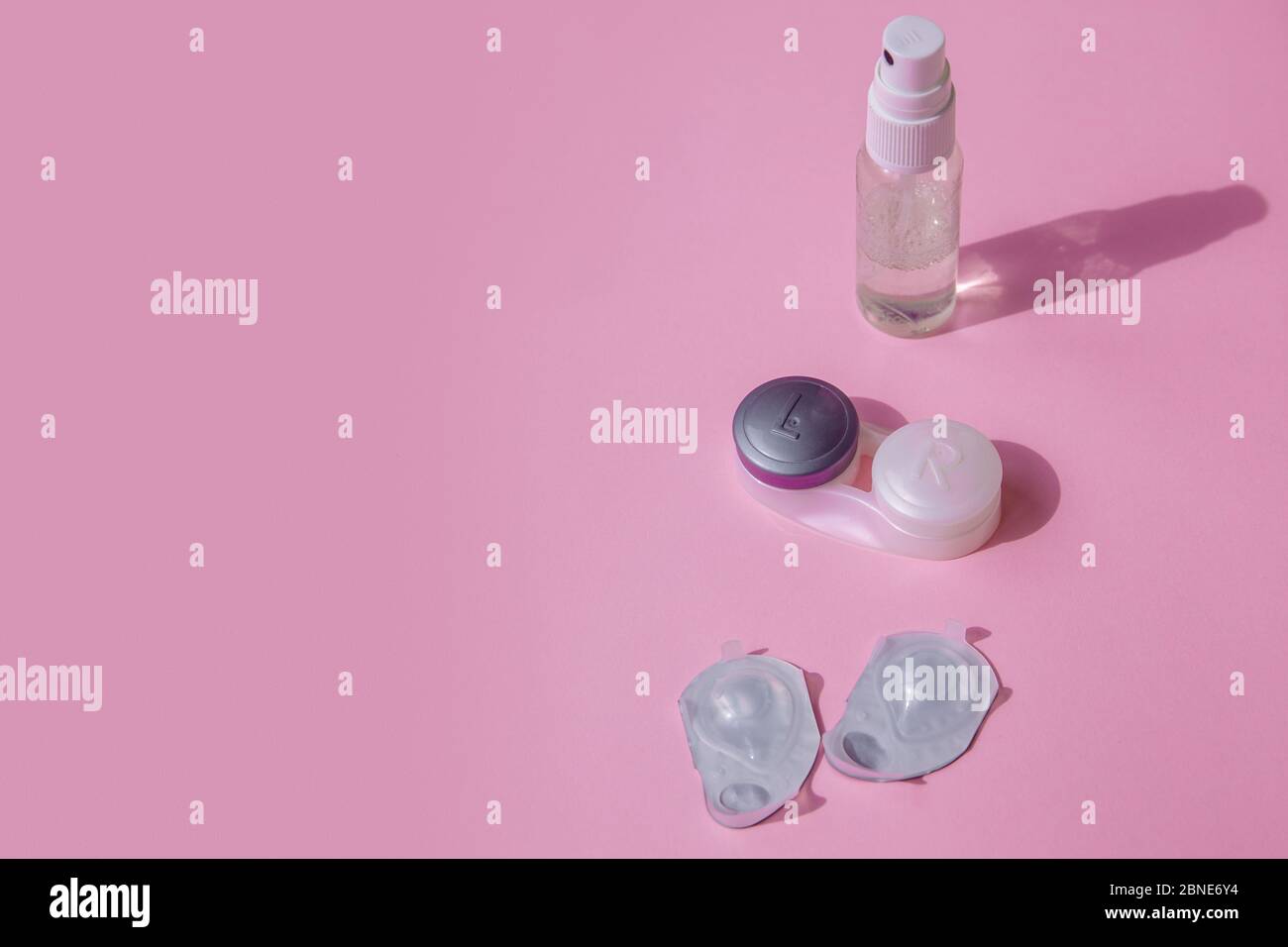 Kit lenti a contatto. La tavola rosa è uno spray per disinfettare le mani, un contenitore per le lenti e blister con lenti. Foto Stock