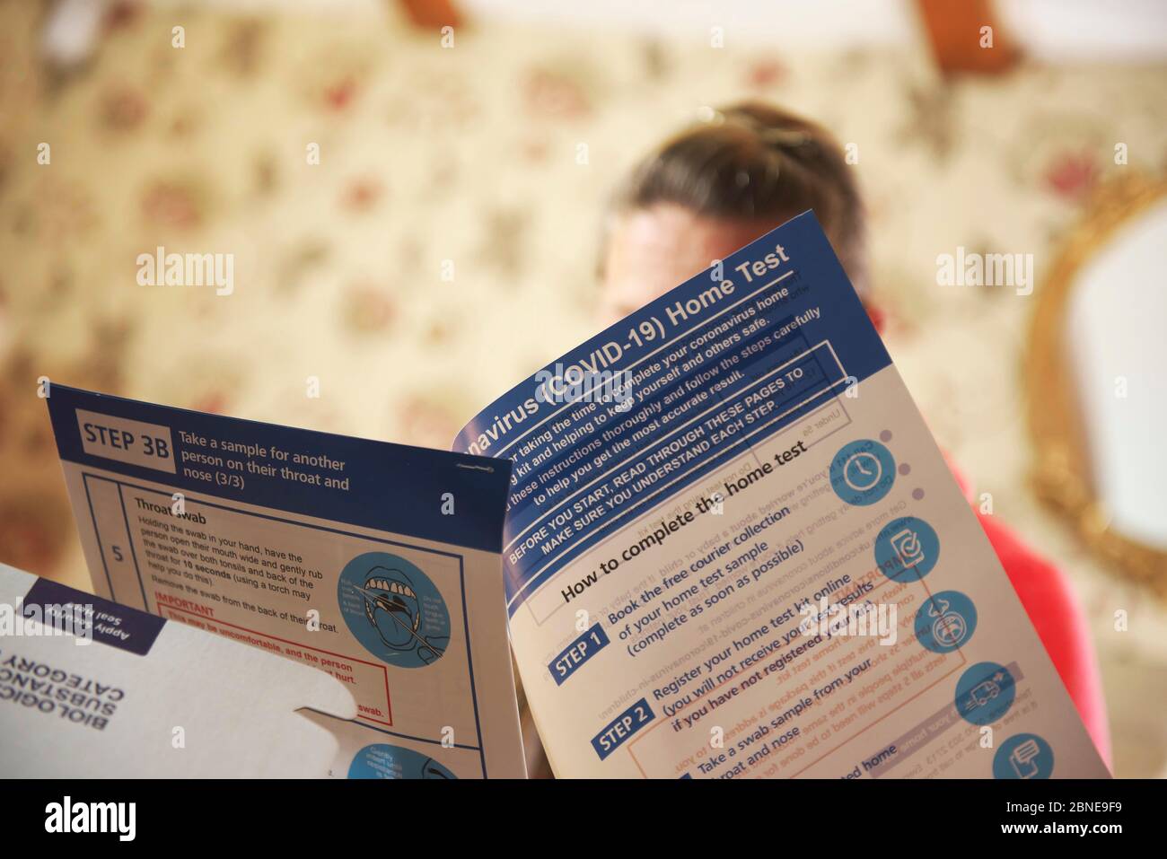 la giovane donna bianca di media età si siede a casa leggendo attraverso il kit di test Covid19 casa fornito dal governo britannico Foto Stock