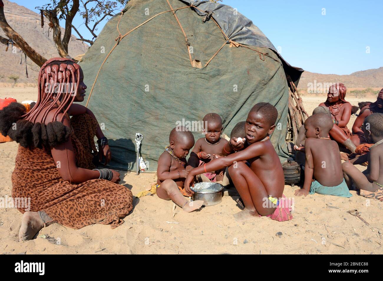 Himba bambini mangiare pasto di mais cotto farina e latte. Marienfuss Valley, deserto di Kaokoland, Namibia. Ottobre 2015 Foto Stock