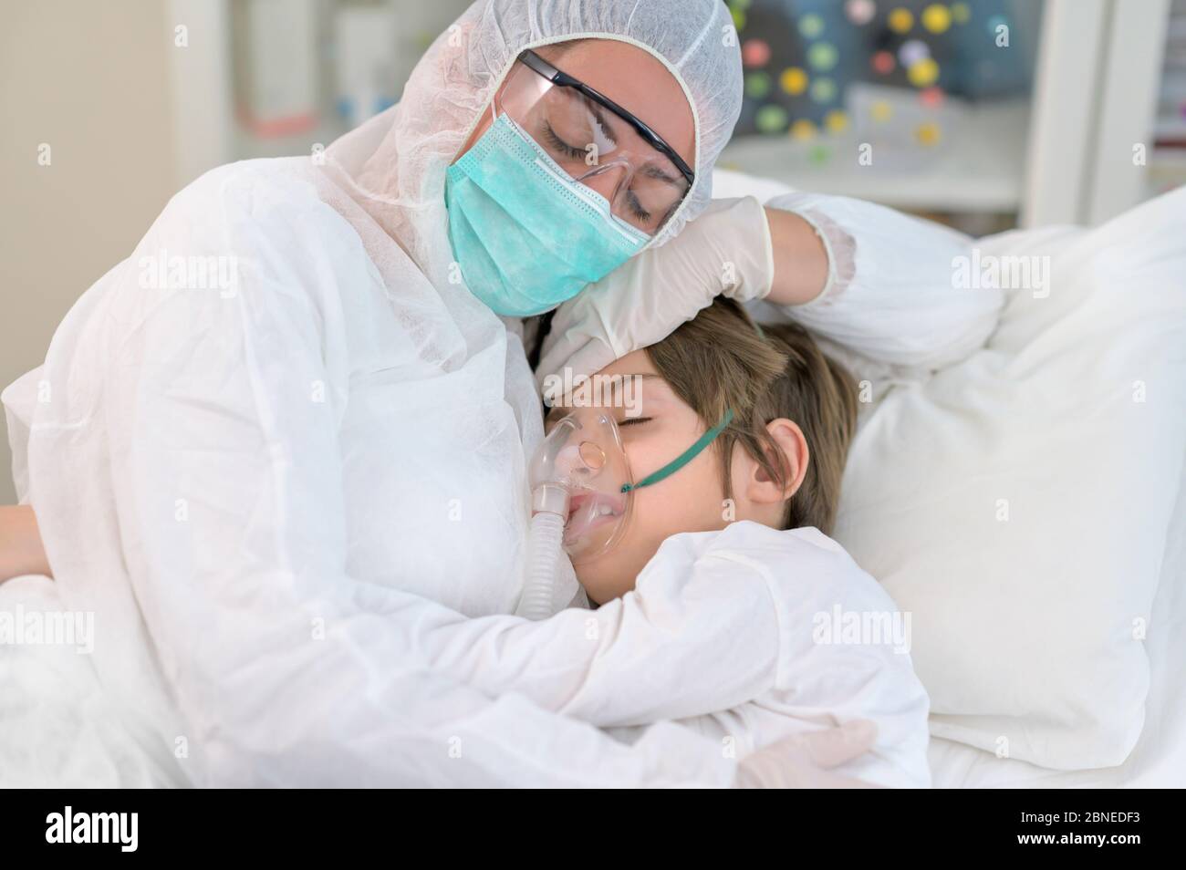 Madre empatica stanca abbracciando e prendendosi cura del suo ragazzo, intubata in ospedale Foto Stock