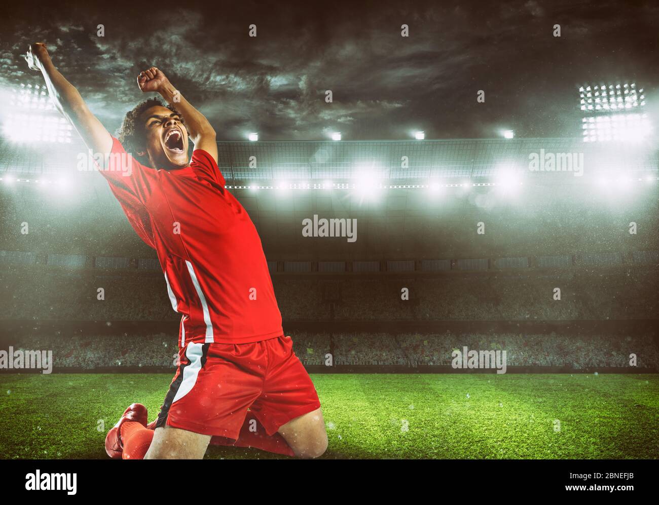 Il calciatore in uniforme rossa gioisce per la vittoria allo stadio Foto Stock