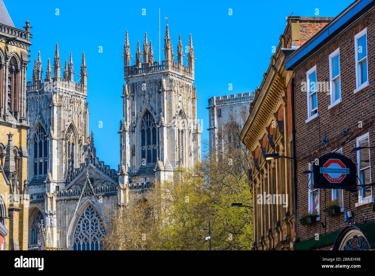 York, North Yorkshire / Inghilterra: Imponente facciata gotica di York Minster con Thomas's of York pub con un cartello sulla destra visto da Museum Street. Foto Stock