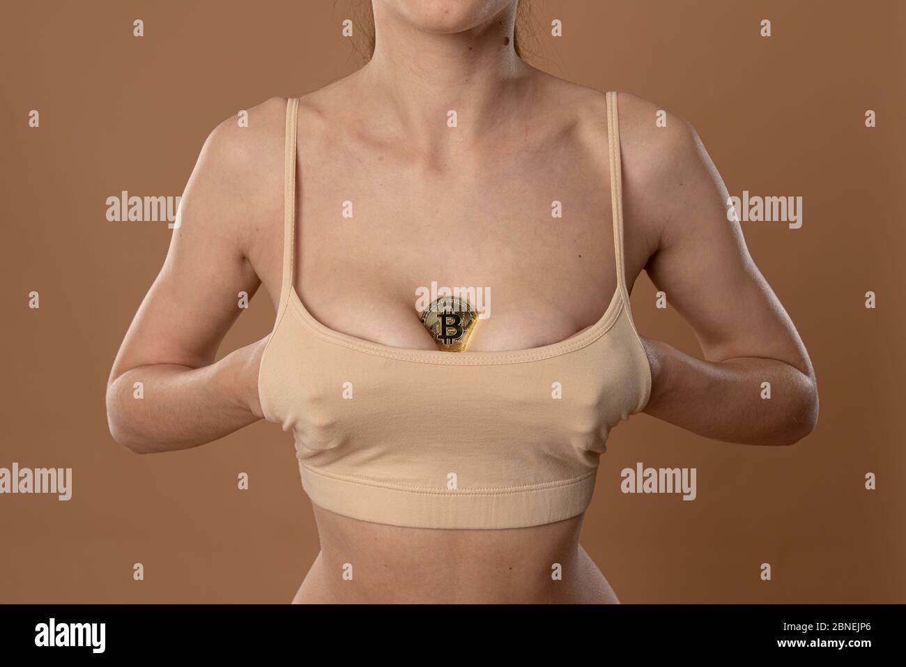 Foto ritagliata di una ragazza sportiva con pelle sana che le tiene sotto il reggiseno beige Foto Stock