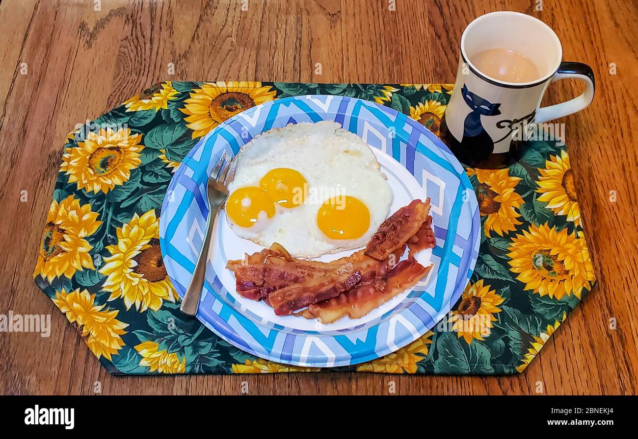 Colazione sul tavolo, con un doppio uovo di tuorlo. Più pancetta e caffè. E una tazza di caffè di gatto. Foto Stock