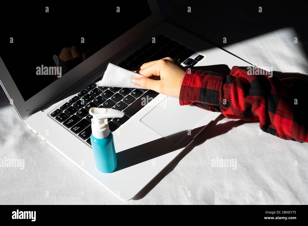 lavoratore che disinfetta il computer dell'ufficio. Disinfezione dei luoghi di lavoro. Foto Stock