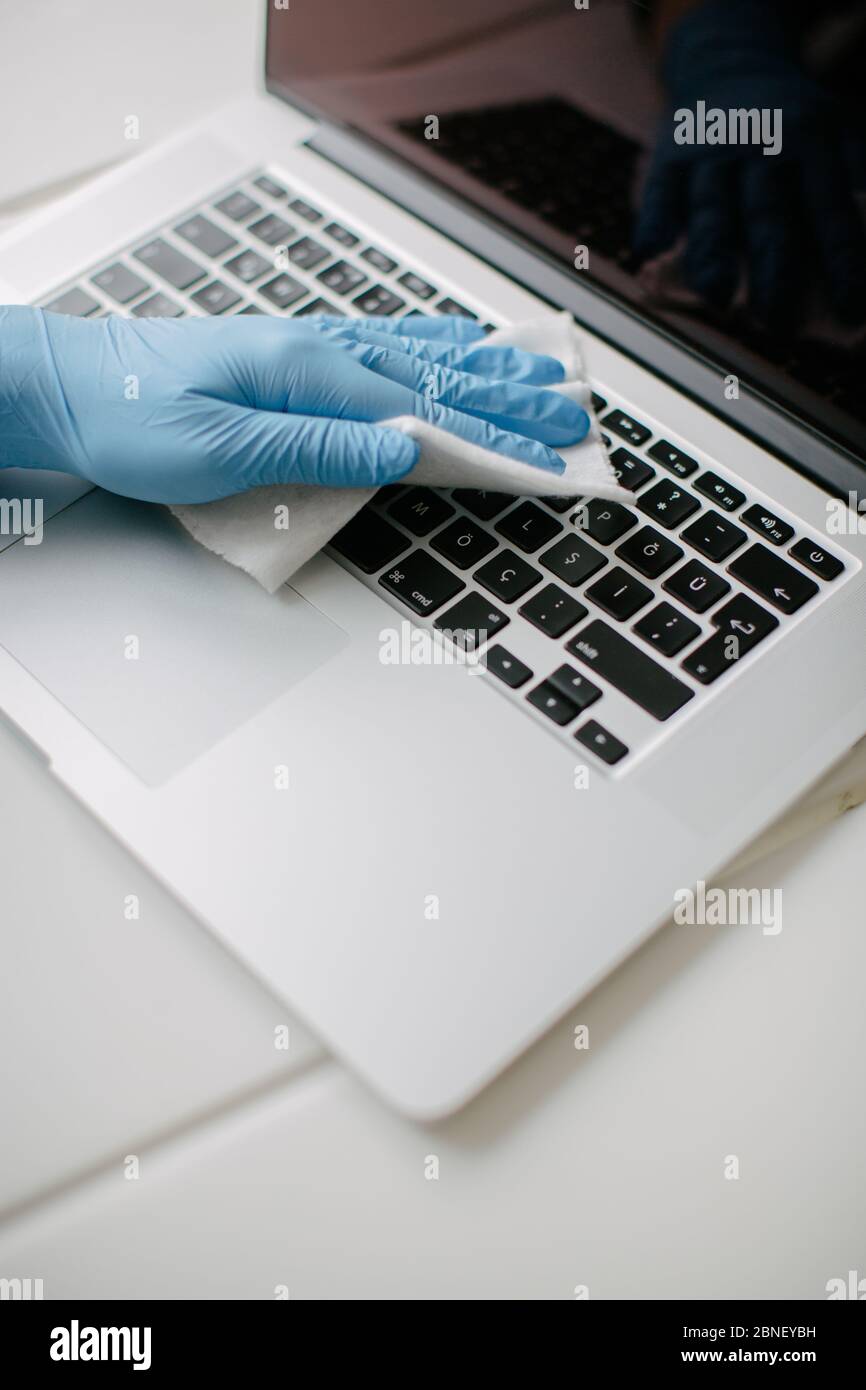 La donna pulisce la tastiera del suo computer per proteggerla da coron Foto Stock