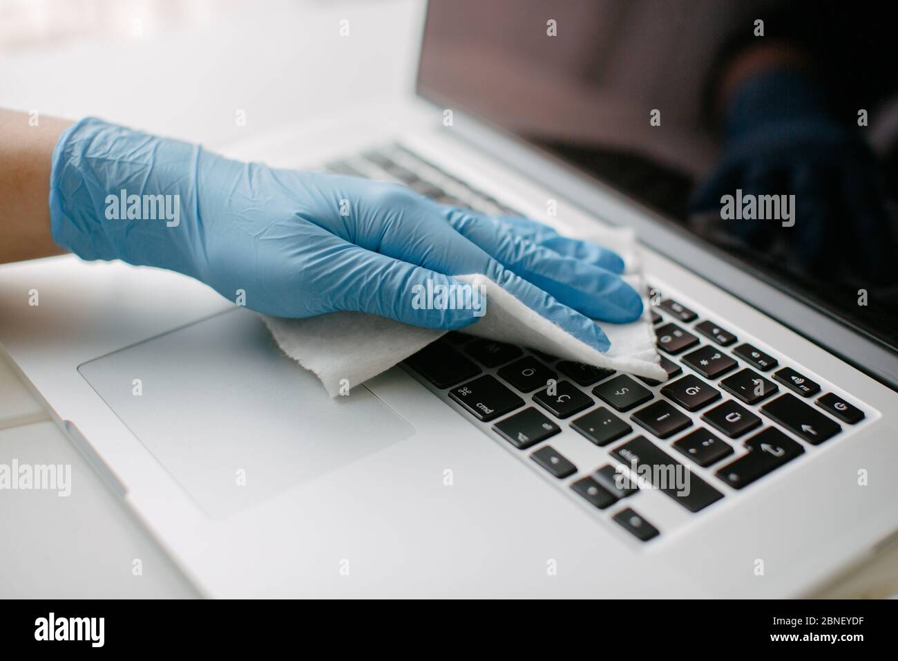 La donna pulisce la tastiera del suo computer per proteggerla da coron Foto Stock