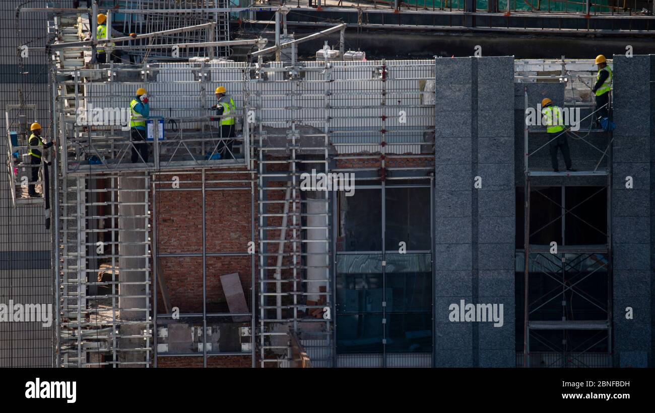 I lavoratori sono appesi fuori da un alto edificio per fare lavori di decorazione esterna nella città di Hai'an a livello di contea, città di Nantong, provincia di Jiangsu della Cina orientale, il 2 aprile Foto Stock