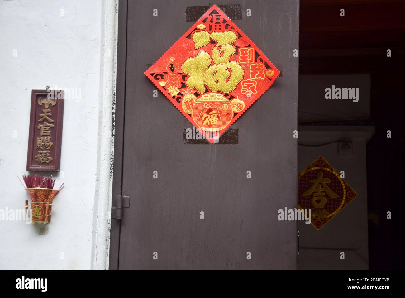 Porta d'ingresso alla casa decorata con felicitiche parole scritte in calligrafia sulla carta rossa. Una traduzione di carattere è felicità. Foto Stock