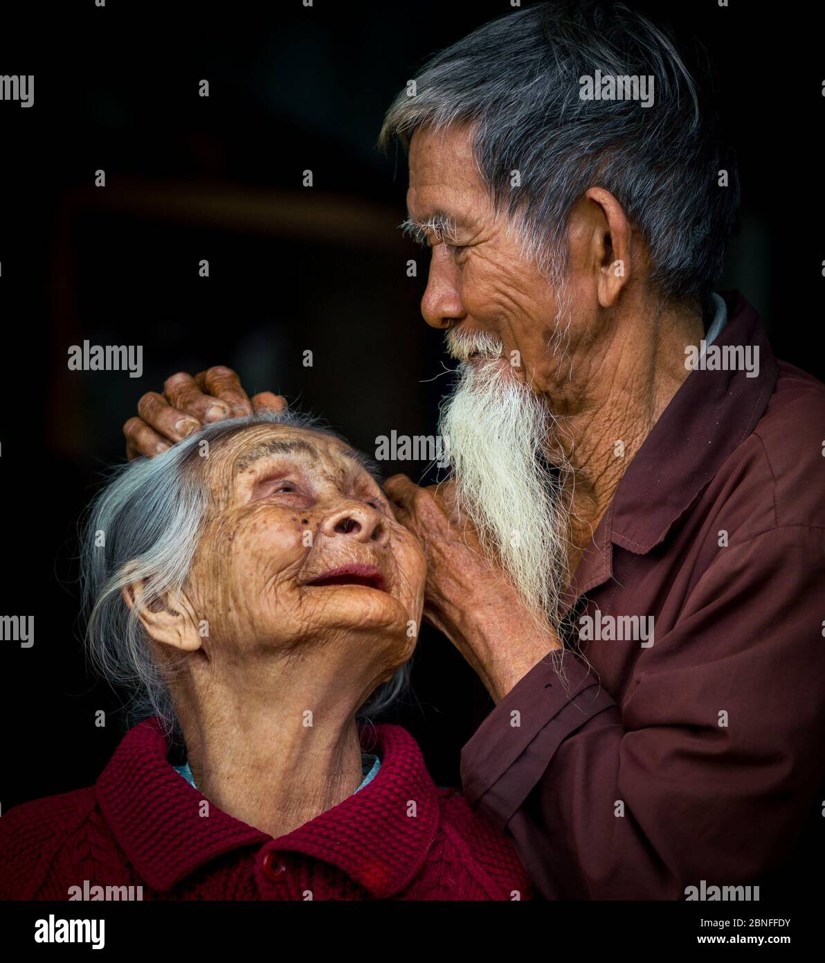 HOI AN, VIETNAM - Mar 14, 2018: Una coppia asiatica con una vecchia signora che guarda il marito mentre il marito sta fissando delicatamente i suoi capelli con la schiena nera Foto Stock
