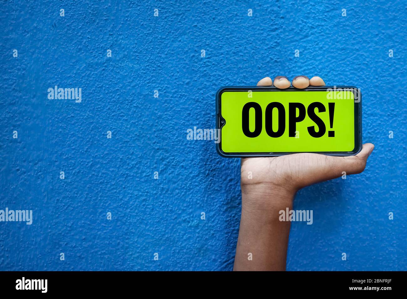 OOPS testo sullo schermo dello smartphone isolato su sfondo blu con spazio per la copia del testo. Persona che tiene mobile sulla sua mano e mostra davanti al sc Foto Stock