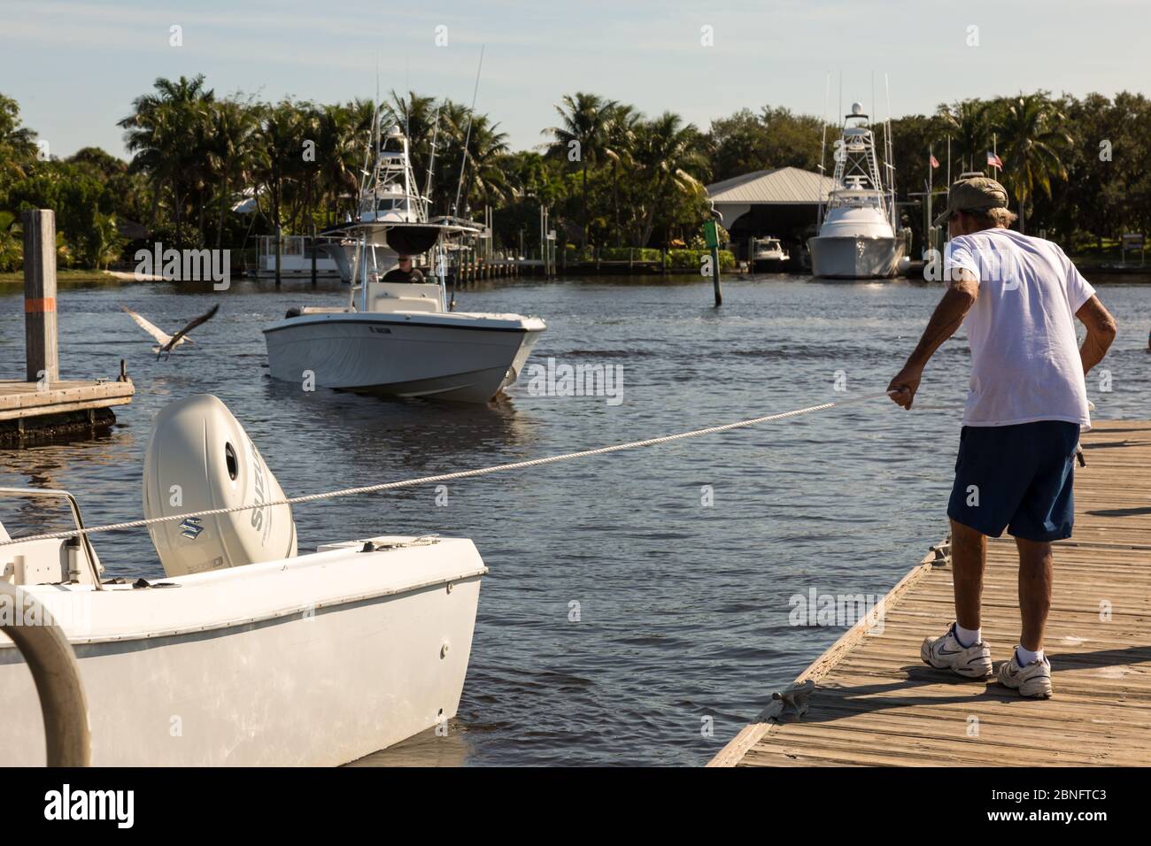 Un uomo tenta di attraccare la sua barca ad un molo al Sandsprit Park a Port Salerno, Florida, USA. Foto Stock