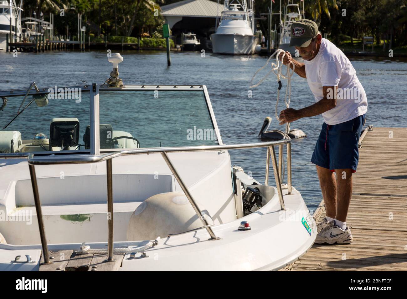 Un uomo tenta di attraccare la sua barca ad un molo al Sandsprit Park a Port Salerno, Florida, USA. Foto Stock