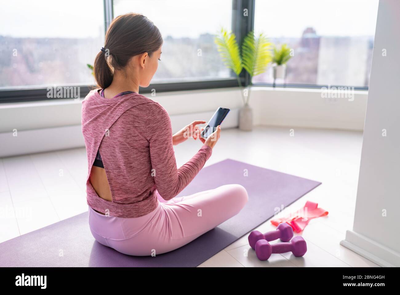 Esercizio stare a casa donna guardare video fitness online sul telefono cellulare yoga allenamento live streaming influenzatore fit ragazza, allenarsi in soggiorno di casa appartamento. Foto Stock