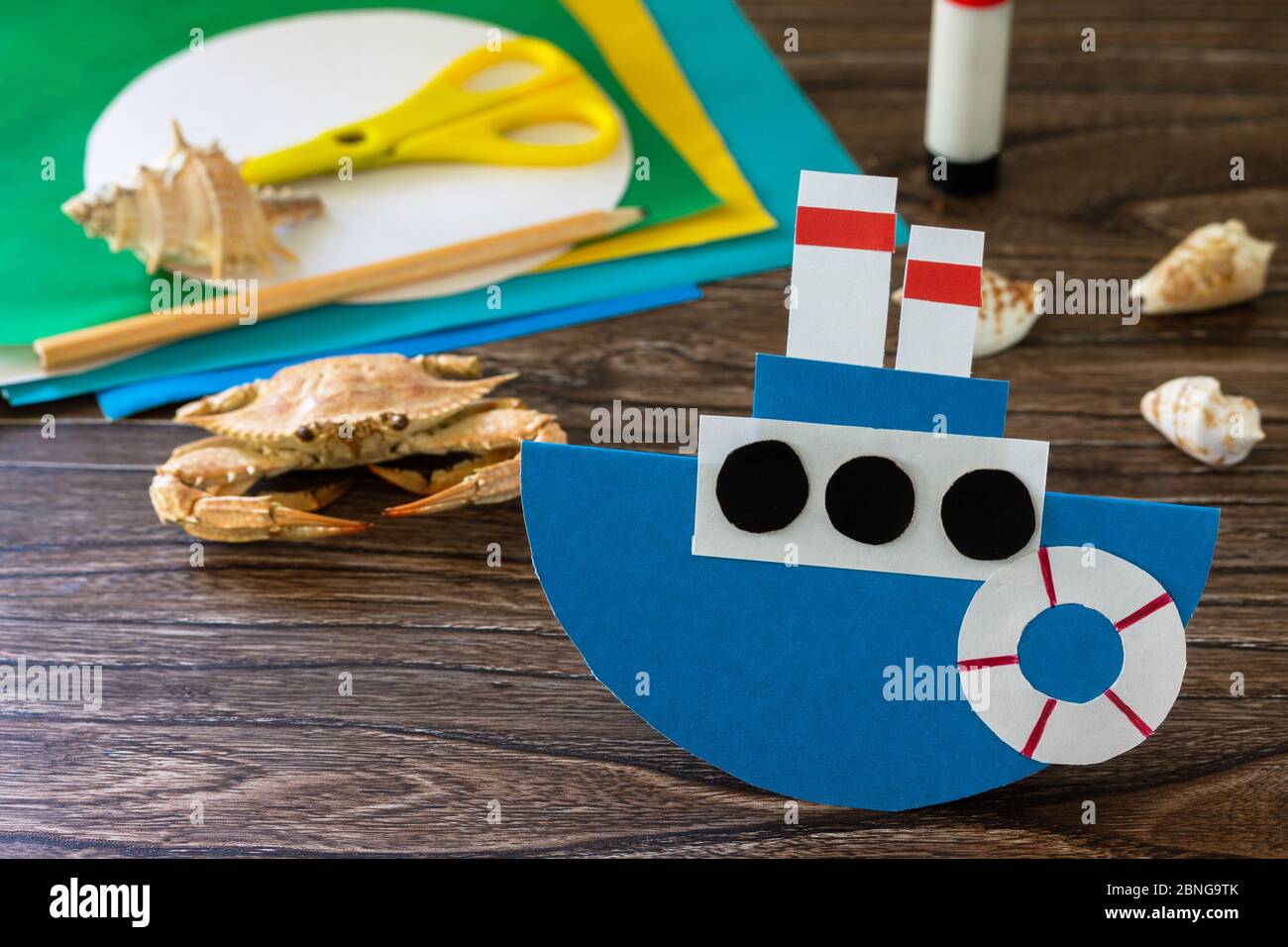 Barca di carta regalo per il giorno del padre su un tavolo di legno. Progetto d'arte per bambini, artigianato per bambini. Artigianato per bambini. Foto Stock