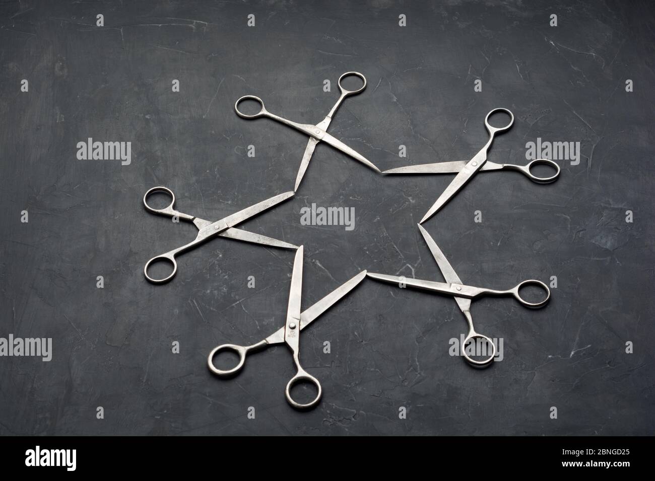 Molte forbici diverse su sfondo scuro che fa la stella. Nero minimo. Disposizione piatta Foto Stock