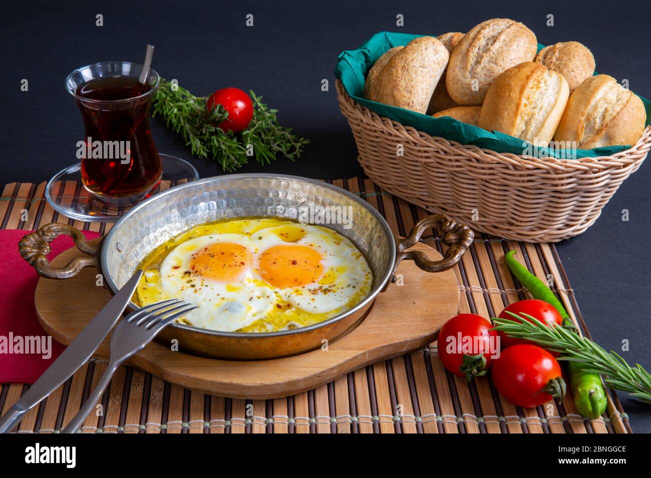 vista dall'alto, colazione tradizionale turca, melemen, uova in una padella di metallo. La colazione viene servita su sfondo nero. tè, uova, pomodori, pane. ristorante Foto Stock