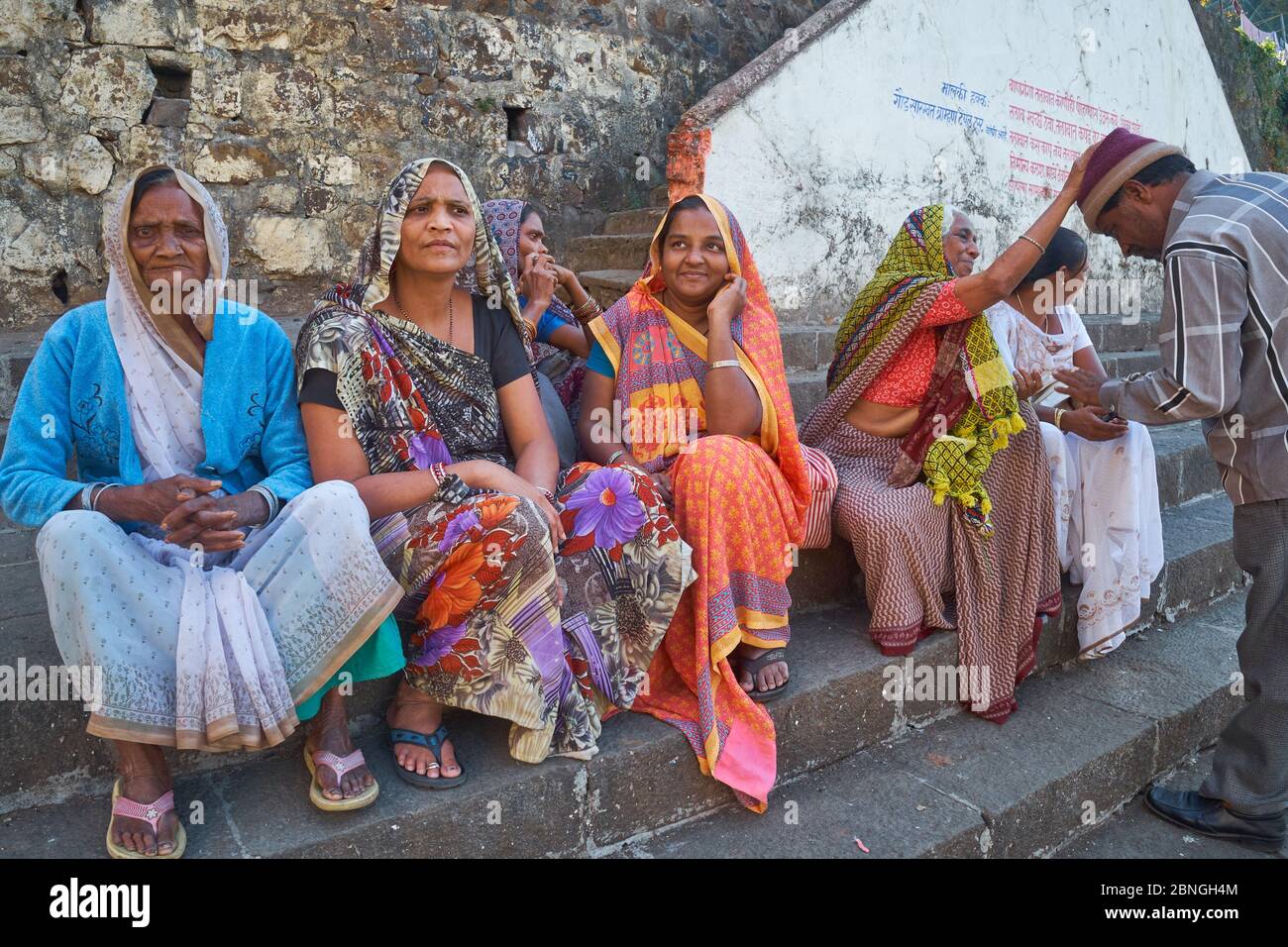 Le donne di una famiglia indù, nel sacro punto indù Banganga Tank, Walkeshwar, Mumbai, India, la donna sulla destra benedicendo un parente più giovane Foto Stock