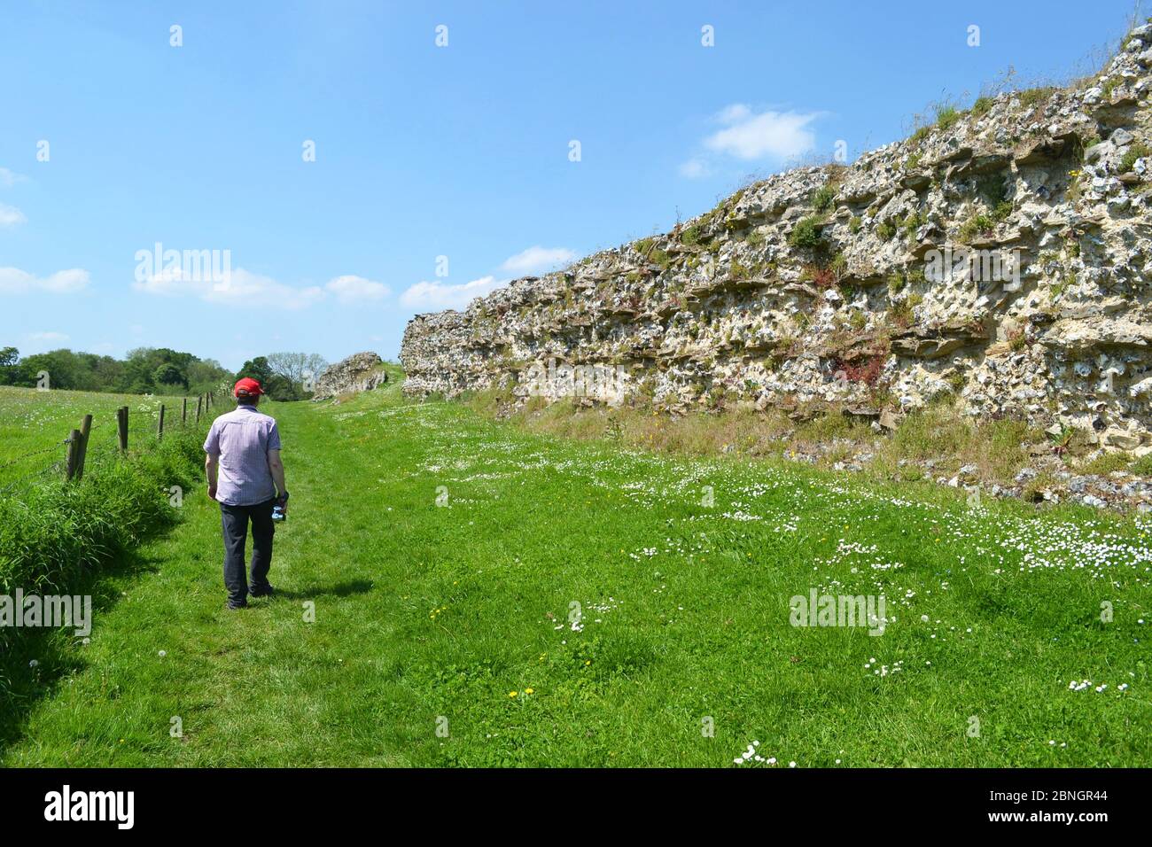 Uomo che cammina lungo le mura romane di Silchester, Silchester, Hampshire, Regno Unito Foto Stock