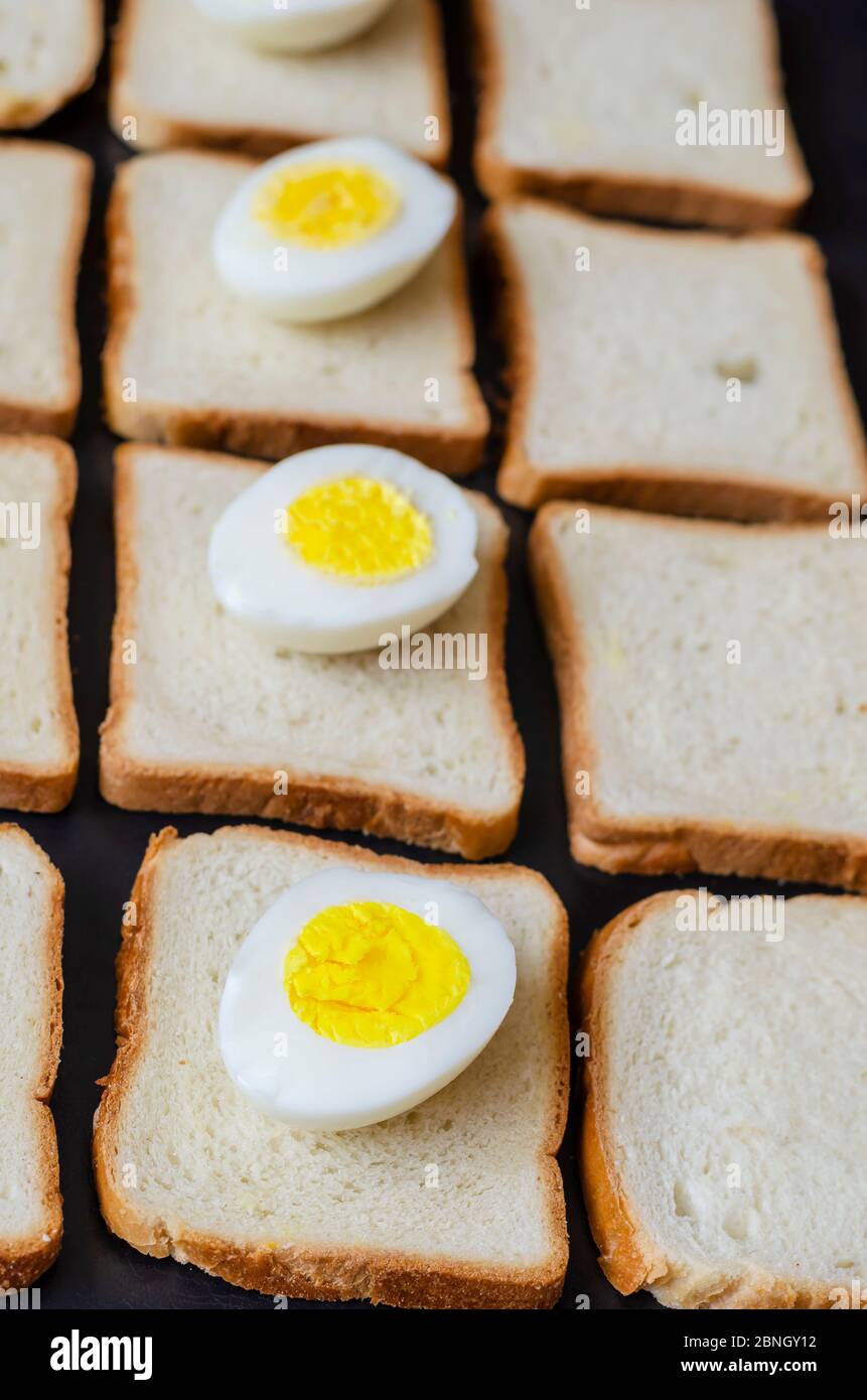 Uova sode a metà e pane tostato. Quattro pezzi di uova di pollo sul pane. Background creativo in una prospettiva di receding. Focus nel foregroun Foto Stock