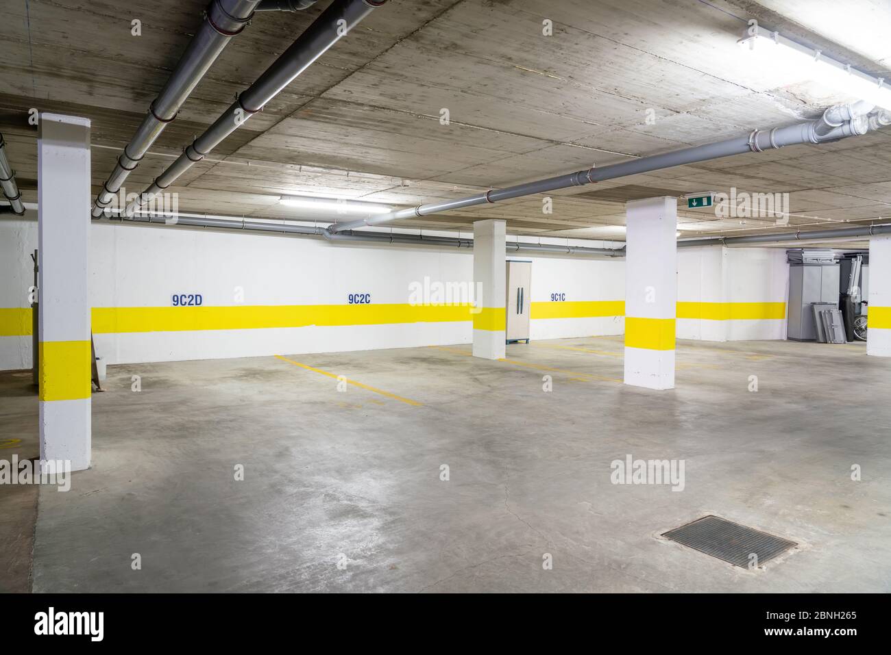 Garage comune per il parcheggio auto in un edificio a più piani con tubi fognari. Foto Stock