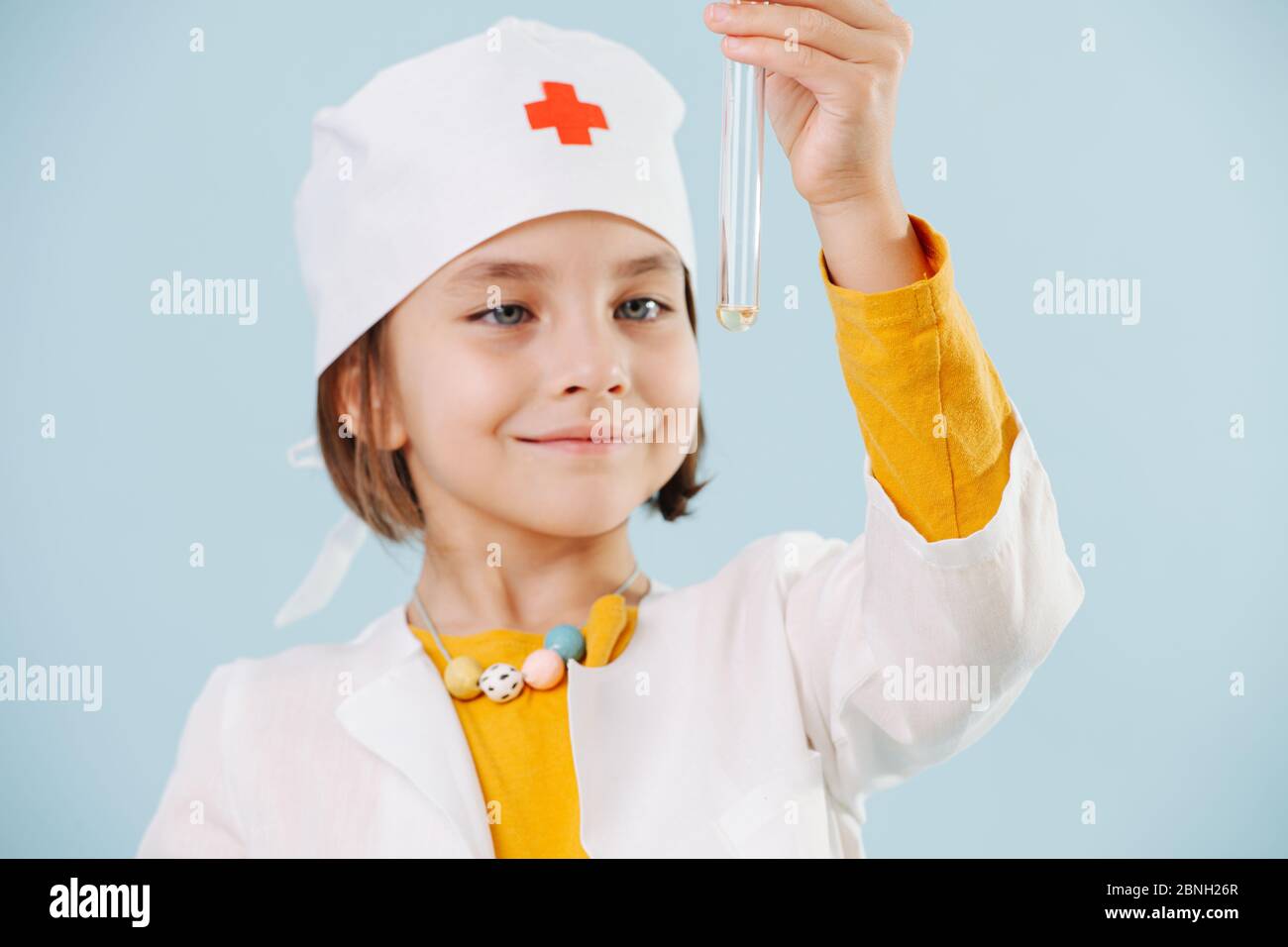 Ragazza piccola felice che gioca un medico guardando il liquido in una fiala Foto Stock
