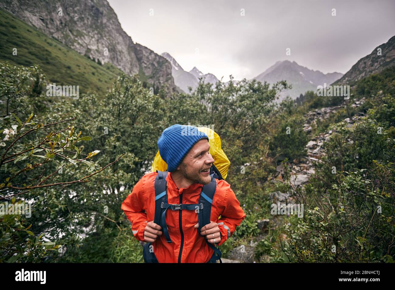 Ritratto di turista felice con zaino grande è nella valle di montagna del parco nazionale Karakol, Kirghizistan Foto Stock