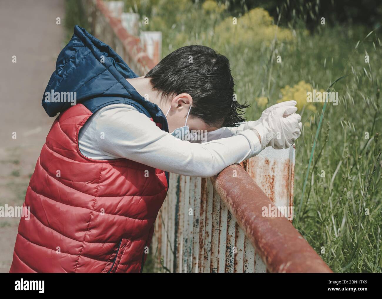 Coronavirus, triste e pensieroso bambino che indossa maschera medica all'aperto Foto Stock