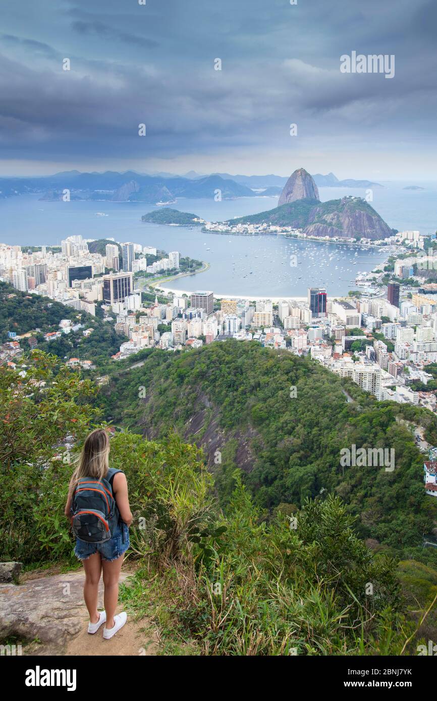 Una donna escursionista che guarda fuori sul paesaggio di Rio a Sugar Loaf montagna dal Parco Nazionale Tijuca, Rio de Janeiro, Brasile, Sud America Foto Stock