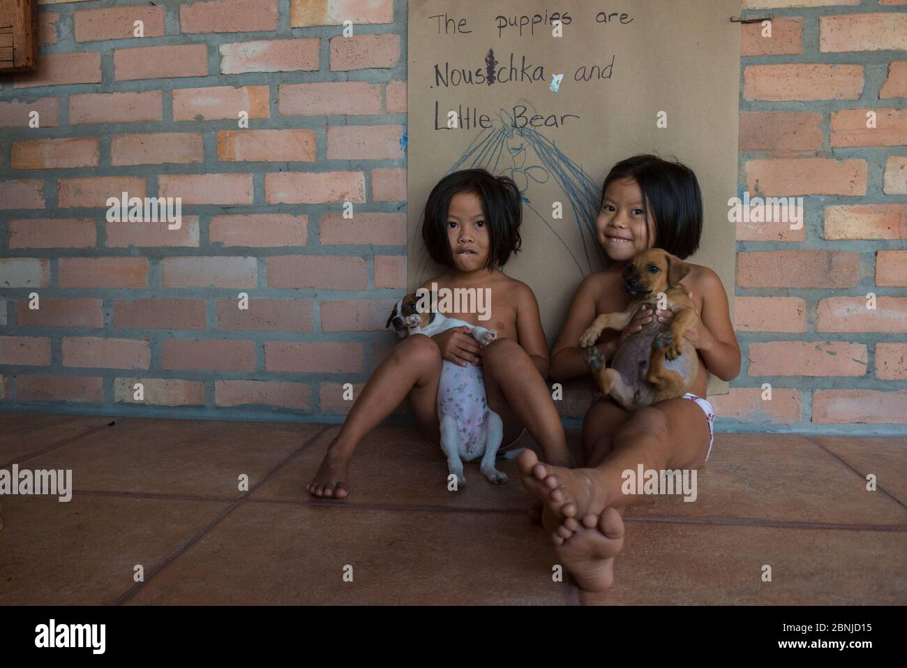 Due bambini che tengono cani domestici, Rupununi, Guyana, Sud America Foto Stock